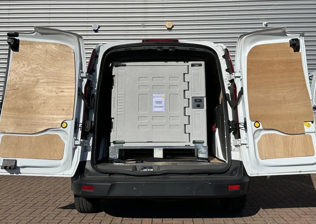 A white delivery van with open doors, showing a large grey temperature-controlled shipping container secured inside.