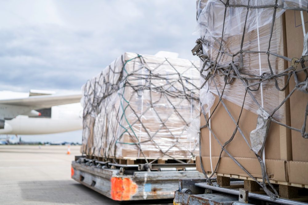 Two loads of secure freight being transported towards an airplane.